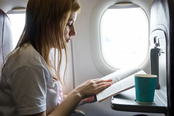 mujer leyendo viajando cómoda en un avión