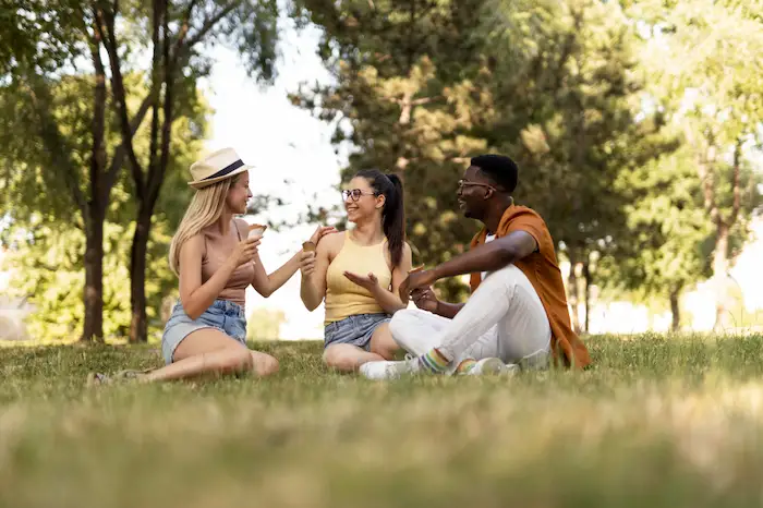 un grupo de 3 amigos conversando sentado en un parque