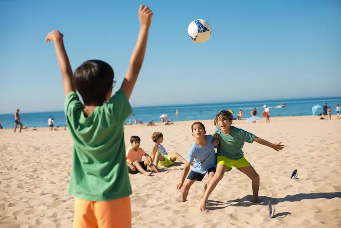 niños jugando futbol en la playa